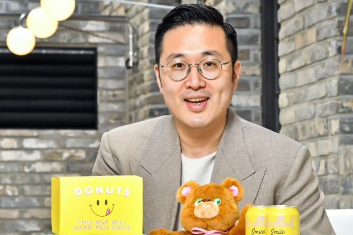 CEO of GFFG Lee Joon-beum poses with coffee and beer products featuring Cafe Knotted designs
