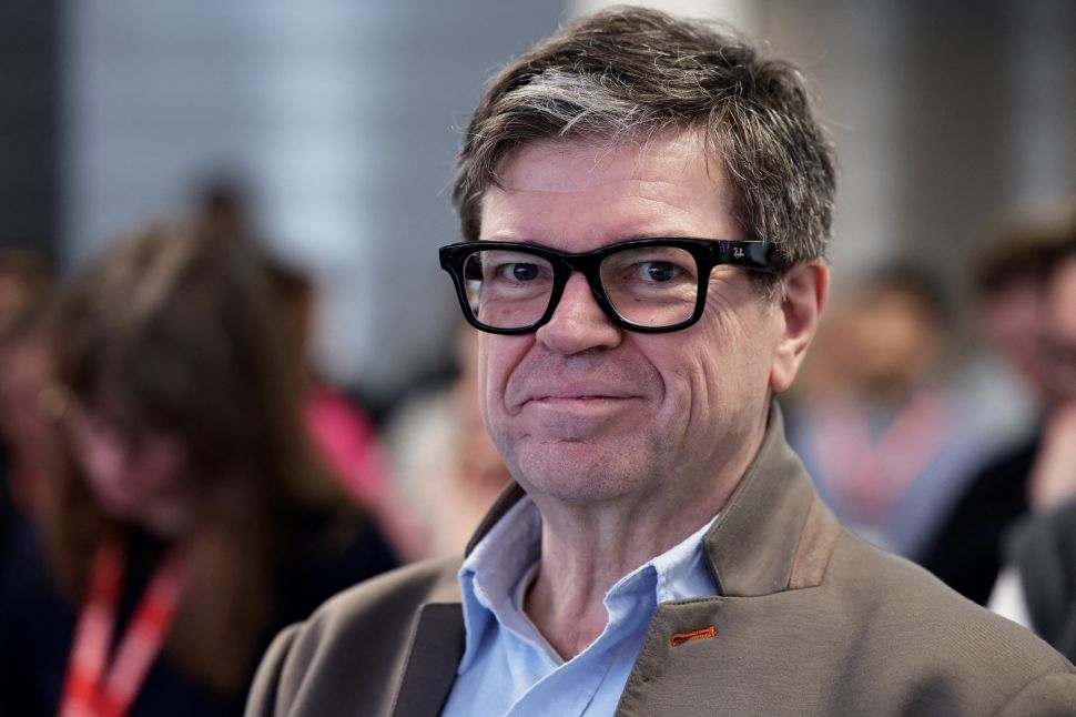 Man in beige jacket and dark framed glasses