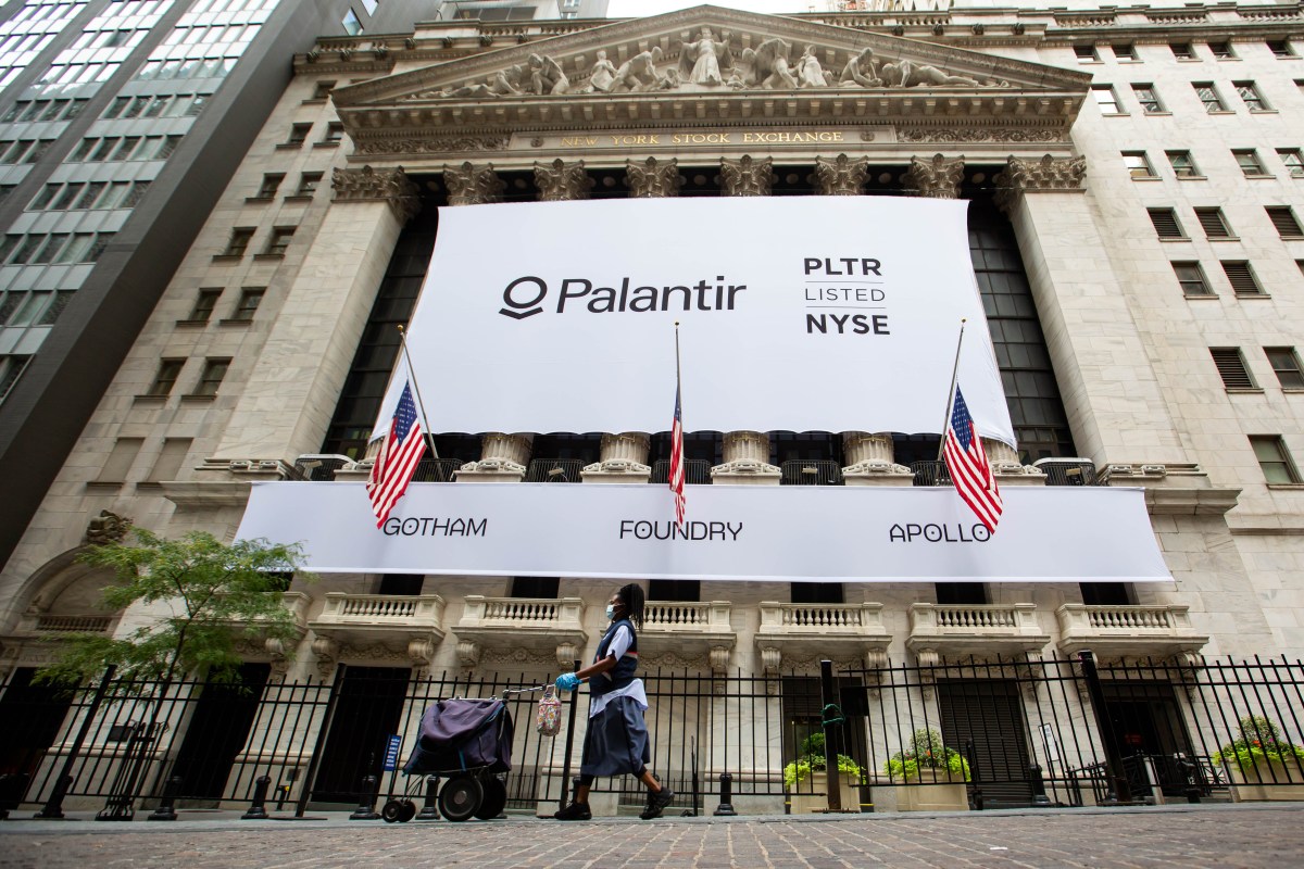 A mail carrier wearing a protective mask passes a banner displaying Palantir Technologies Inc. signage during the company's initial public offering (IPO) in front of the New York Stock Exchange (NYSE) in New York, U.S., on Wednesday, Sept. 30, 2020.