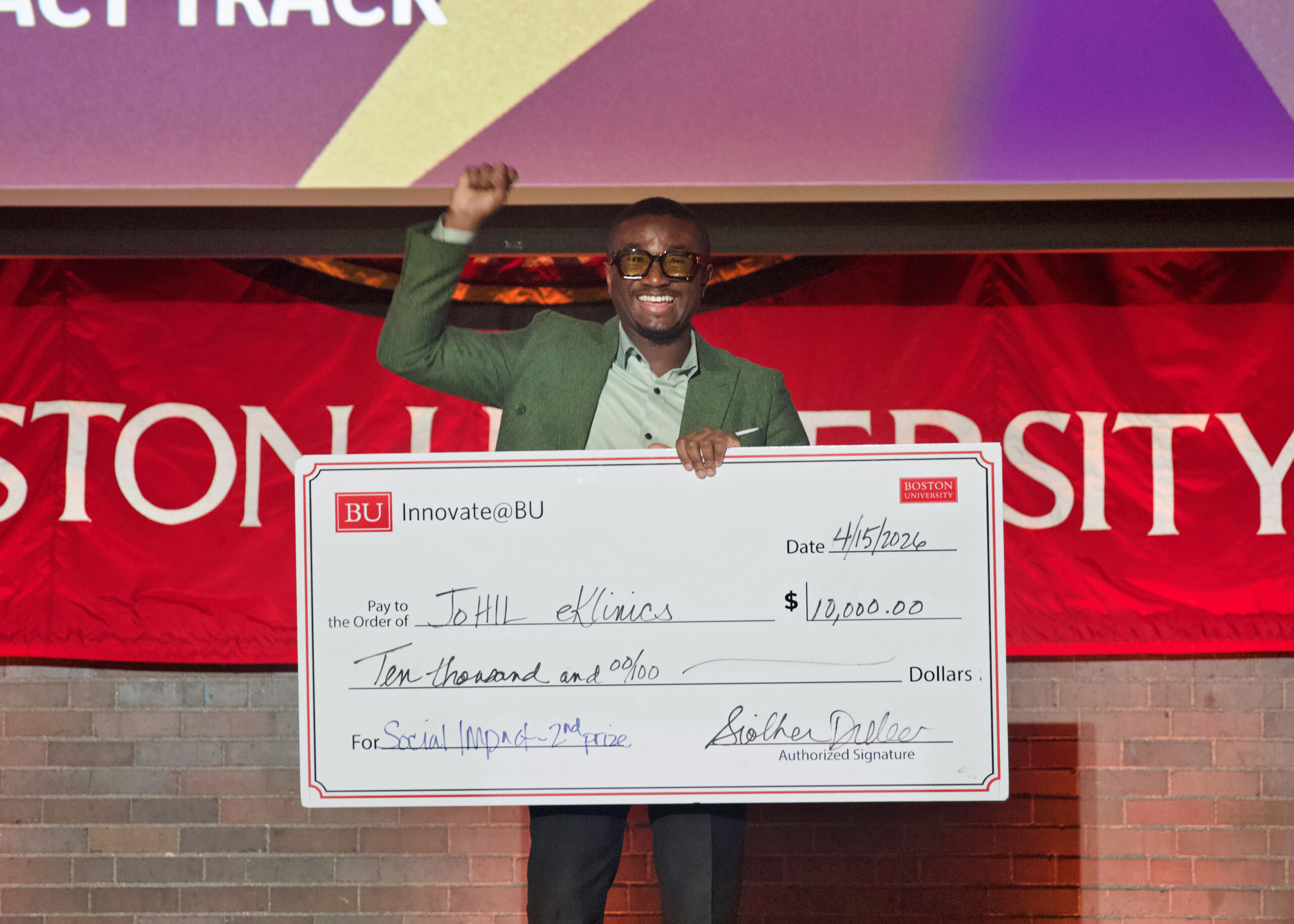 Samuel Amoako-Kusi celebrates with his second place prize, a $10,000 check for his social impact venture JoHil eKlinics. Photo: Megan Jones
