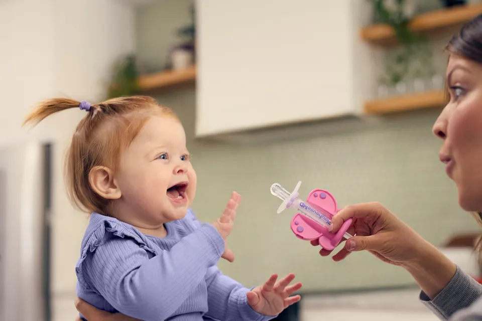 A Playhouse MD medicine dispenser designed to look like a butterfly being used with a young child.