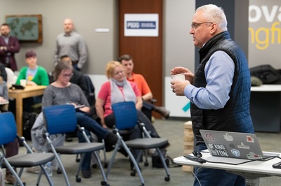 Paul Magelli talks while standing in front of a group of seated people