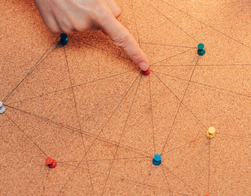 Finger connecting dots on a cork board network concept