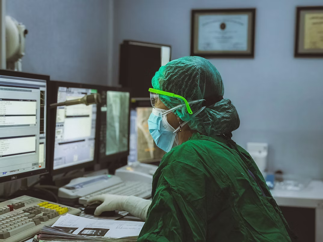 A clinician in scrubs using a computer.