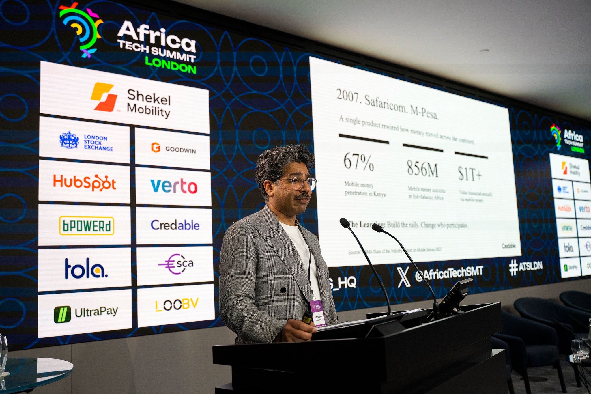Nadeem Juma presenting at Africa Tech Summit London with slides on M-Pesa, mobile money growth, and African credit infrastructure.