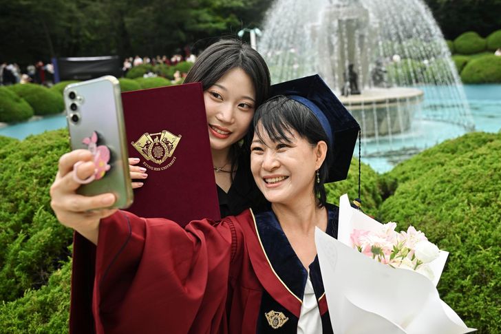 A graduate and a family member take photos to mark the graduation at Kyung Hee University in Dongdaemun District, Seoul, Aug. 20, 2025. Korea Times photo by Jung Da-bin