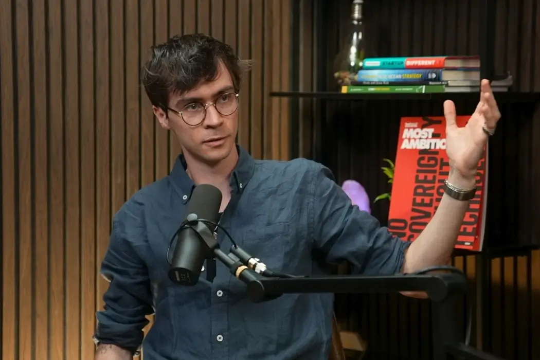 Nick Frosst gestures while speaking into a microphone on The BetaKit Podcast.