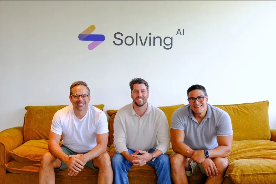 Three members of the Solving.AI team sit together on a couch, all facing the camera.