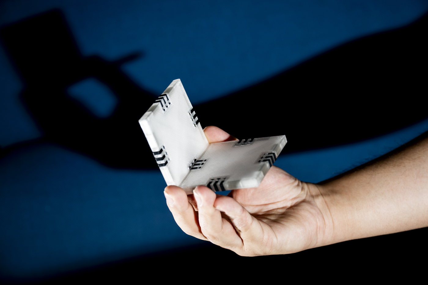 A hand holds a prototype of the NextTile building block toy.