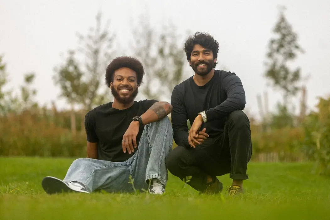 The founders of The Wellness Company sit together on a patch of gren grass