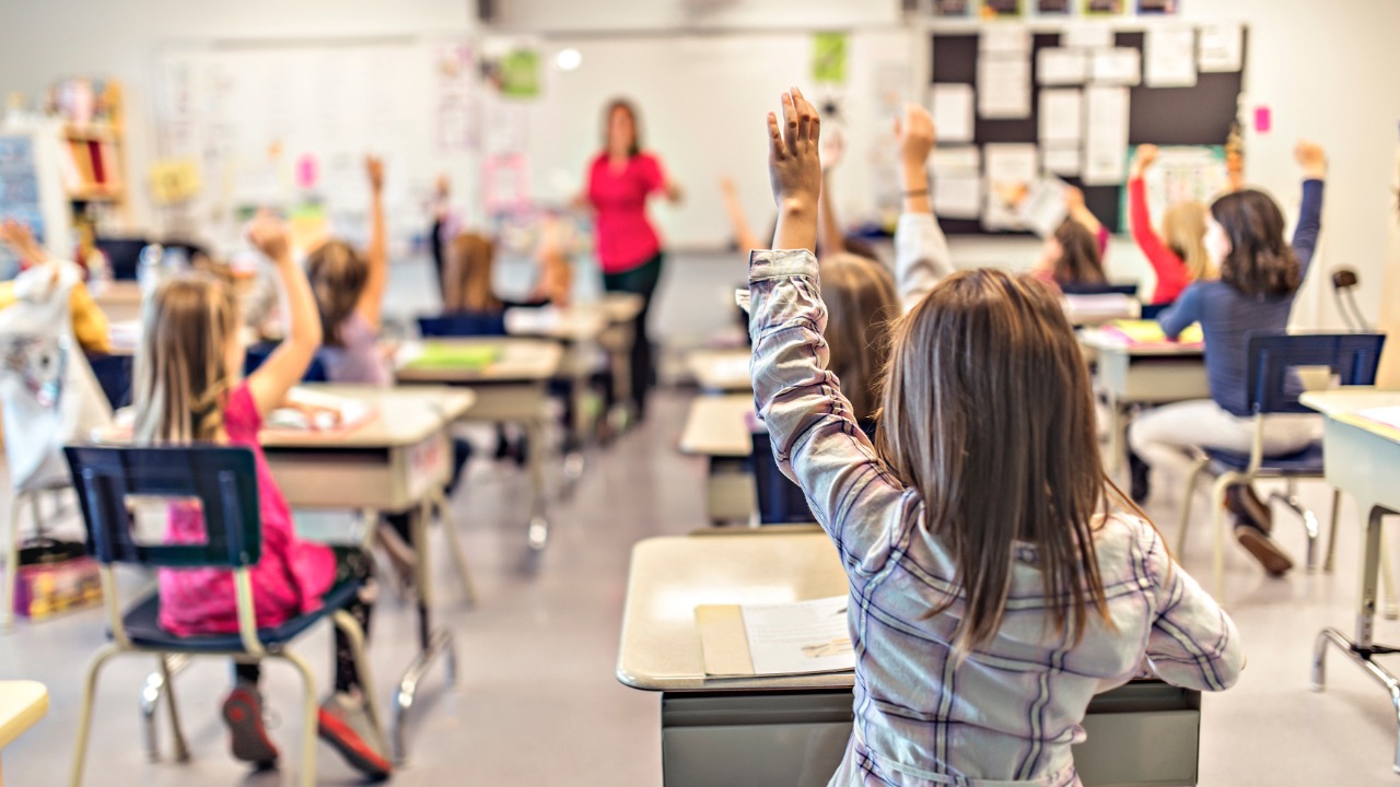 Students raise their hands during a lesson in an elementary school classroom