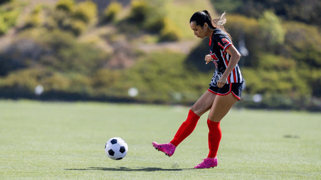 Youth soccer player kicks a ball during a game on an outdoor field