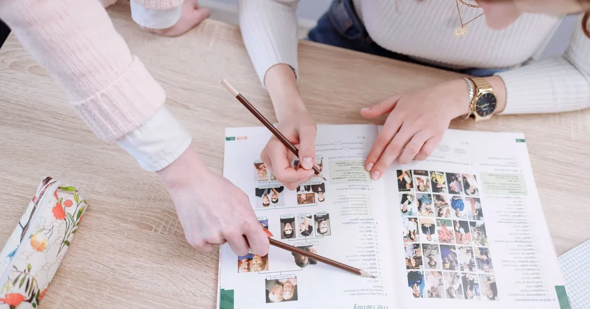 Students working together on an assignment, pointing at pages in a textbook.